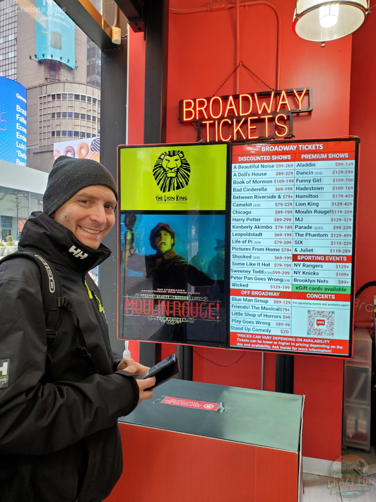 Kris in front of the discounted Broadway show board on the 3 Day Trip to New York.