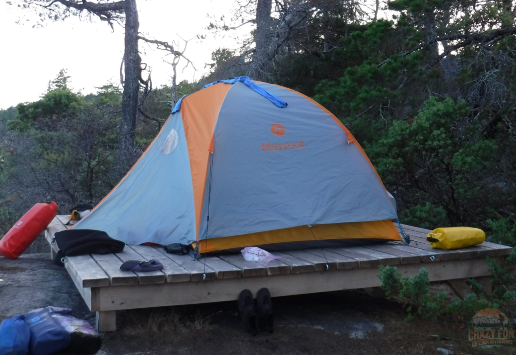 Have an awesome day Kayaking with your Dad by bringing dry bags. The dry bags are beside a tent on an elevated wood pad.