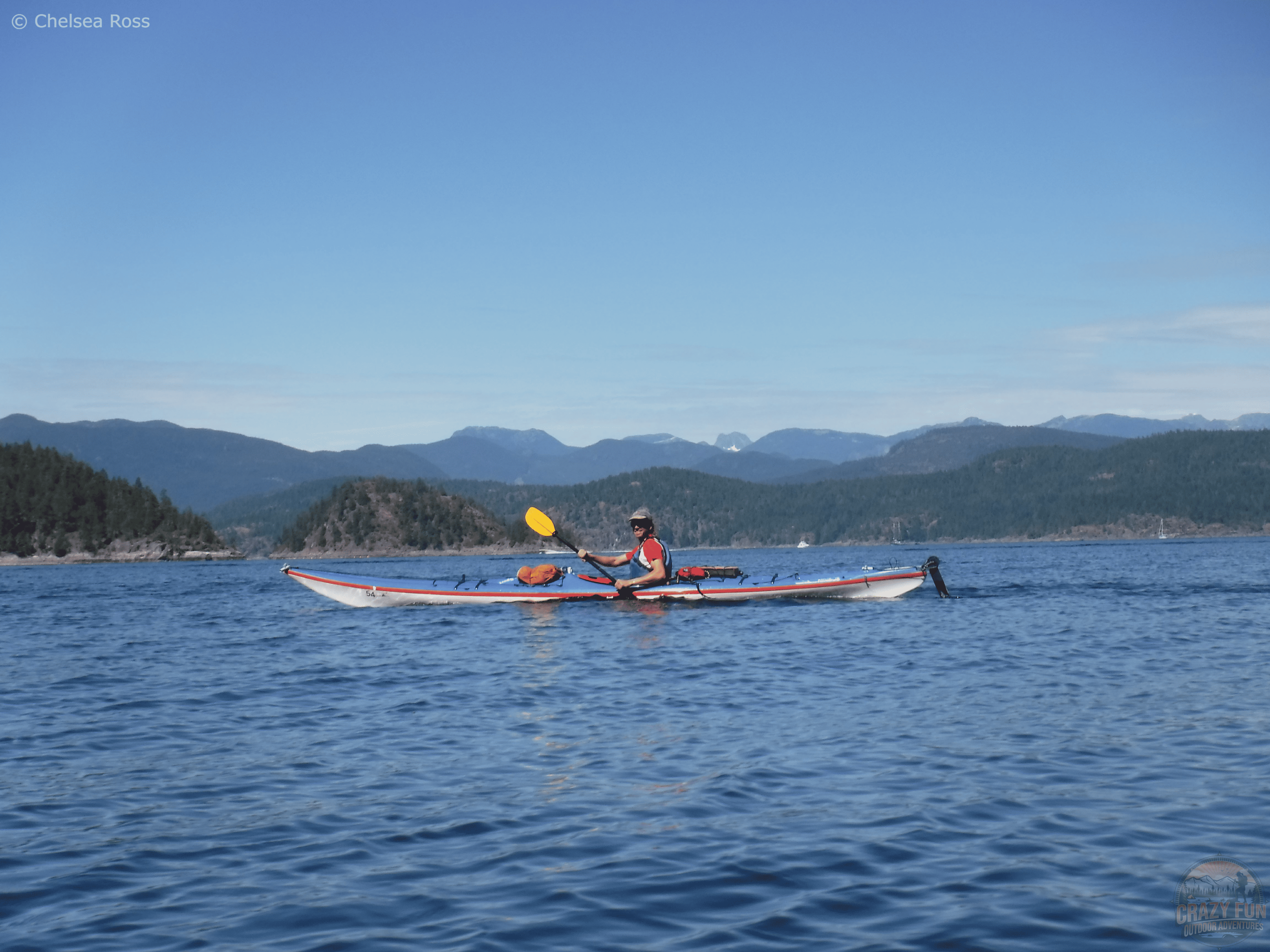 Have an awesome day kayaking with Dad by going on a day trip. A man is sitting in his kayaks with a beautiful mountain backdrop.