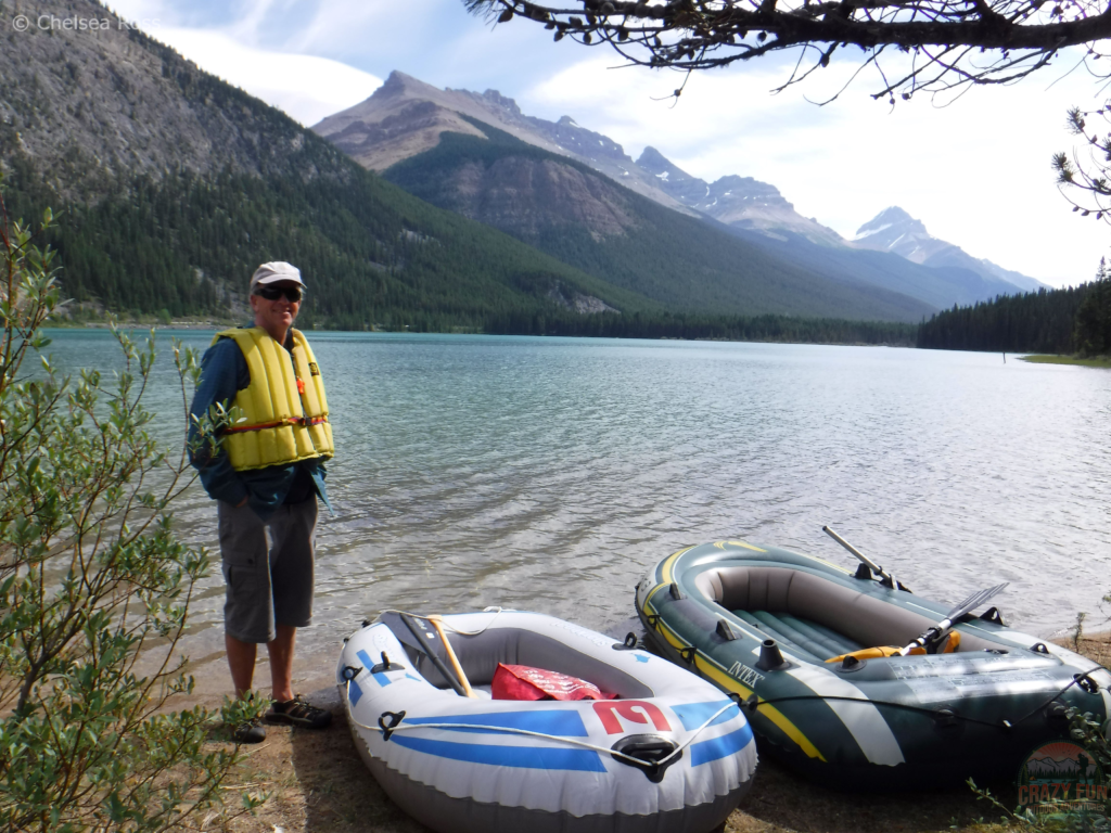 Man standing beside two rafts with Waterfowl Lakes in the background.