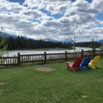 Nice weekend getaway near me includes Becker's Chalets. A yellow, blue and red chair sit overlooking the Athabasca river and the mountains in the background.