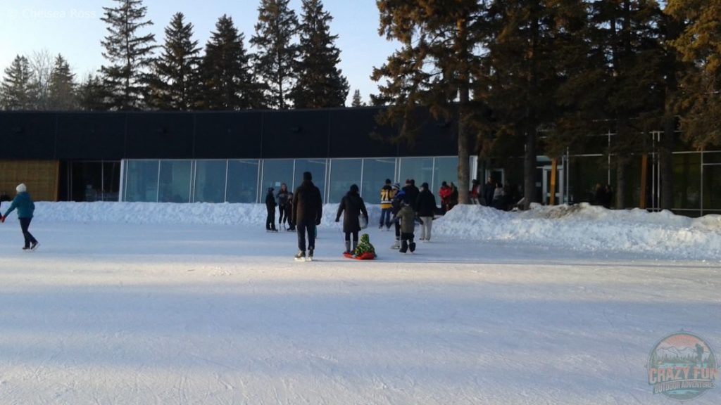 Looking towards the heated building where we take off our skates. People are in front of it entering and exiting. 