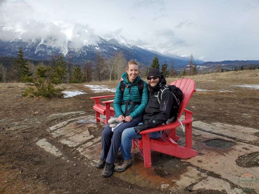 Romantic winter Jasper hikes include Old Fort Point. Couple sitting on a red chair.