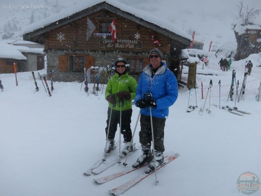 Two people standing in front of Chalet Restaurant Le Bois Pin. 