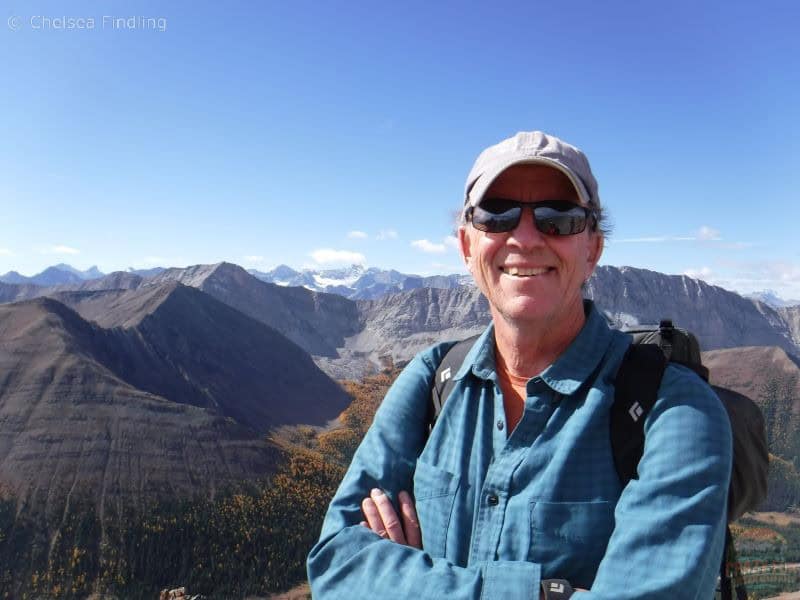 Best Hiking Gifts for Dads: sunglasses. Man wearing sunglasses with a baseball cap and the mountains behind him.