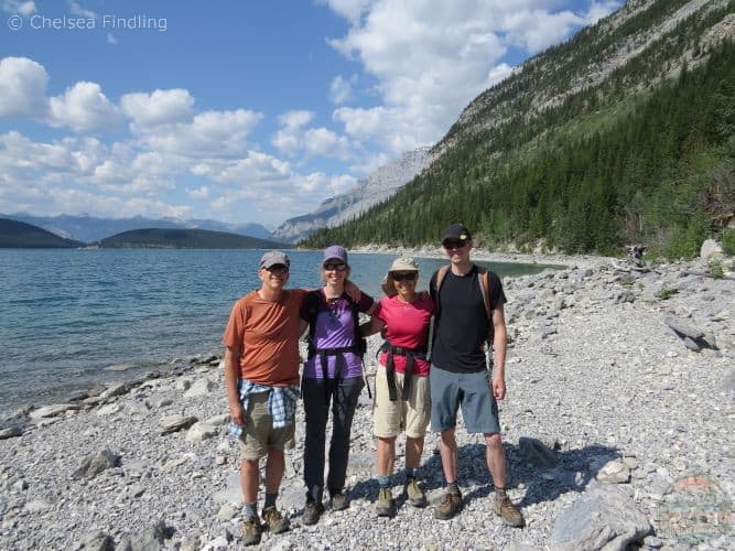 Best Hiking Gifts for Dads: Arc'tyrx shorts that a man is wearing on the far right. Three people to the left of him with Lake Minnewanka behind them.  