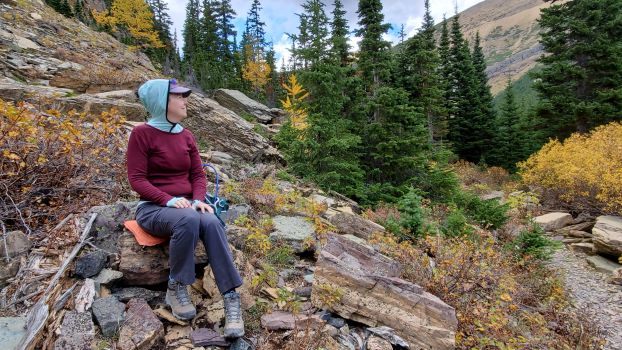 Red and green Minus33 Merino Wool shirts on lady sitting on rock.