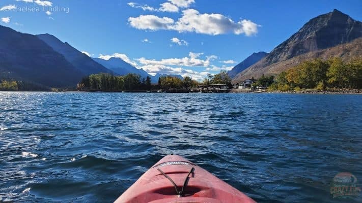 Person kayaking on the choppy Waterton waters in Alberta with mountains in the background. 