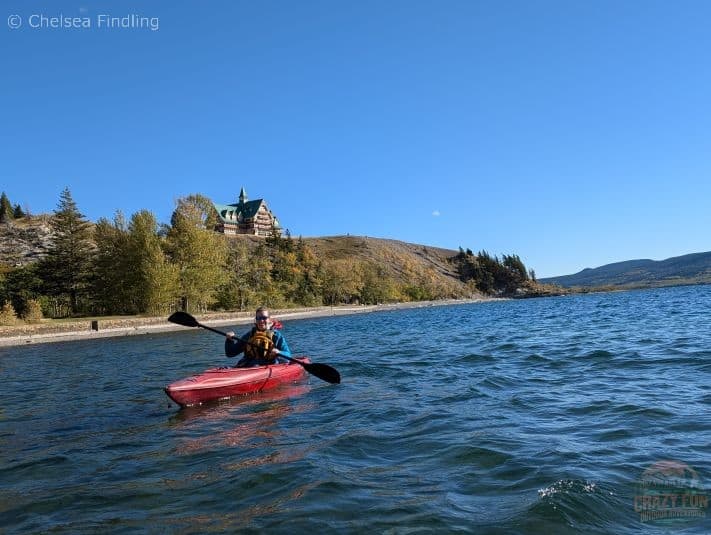 Kayaker paddling on choppy waters of Waterton Lake in Alberta with the Prince Of Wales Hotel in the background.