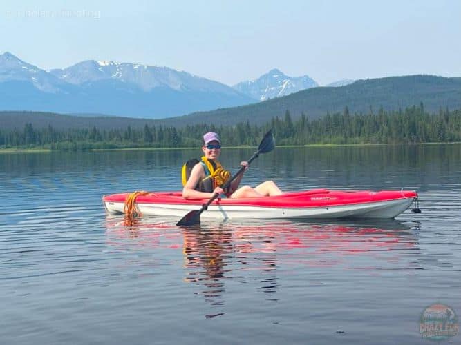 A person in a kayak on calm waters of Pyramid Lake in Jasper, with mountains in the background.