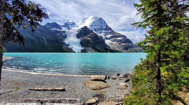 Turquoise waters of Mt. Robson's Berg Lake beside the trail, surrounded by rugged mountains and glaciers.
