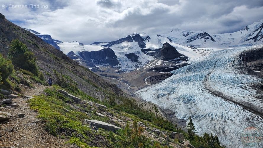 View of the Robson Glacier with rugged mountains rising behind and a rocky trail on the left side of the frame.