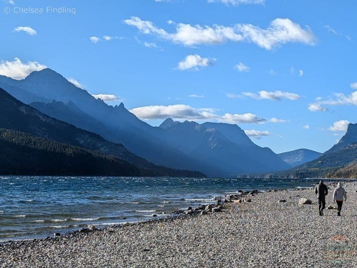 A rocky beach beside Waterton Lakes with mountains on the side. 