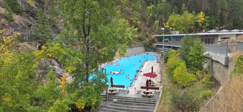 People relaxing in Radium Hot Springs pools surrounded by mountains.