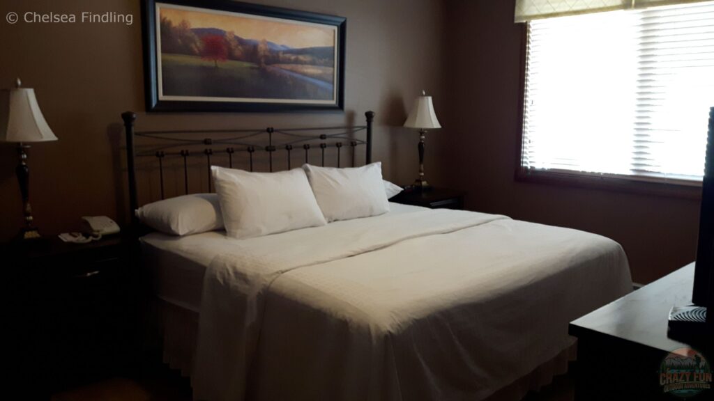 Looking at a bed inside a guest room at Bighorn Meadows Resort showing interior furnishings and a comfortable sleeping area.