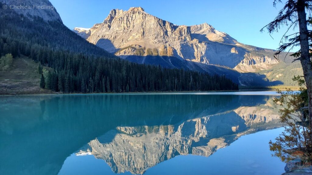 Scenic view of Emerald Lake in the Canadian Rockies showing turquoise water surrounded by mountains, trees, and lodge-style accommodations along the shoreline.