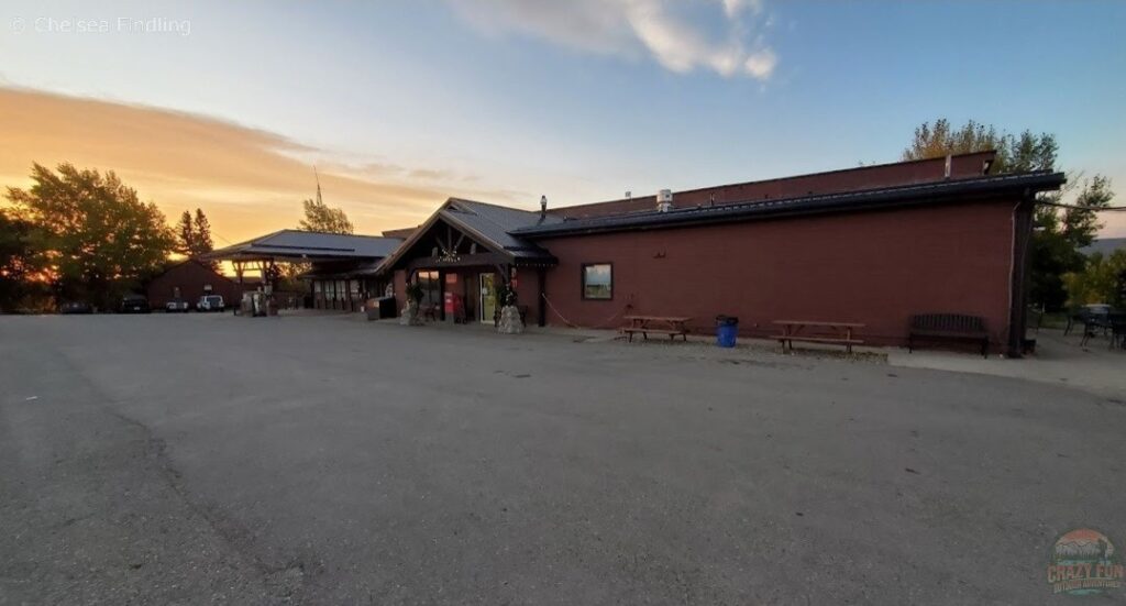 Exterior view of Bear Country Inn & Suites showing the building, gas station and picnic tables. 