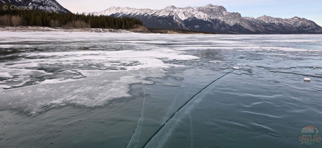 Clear blue ice on Abraham Lake revealing visible layers and thickness beneath the surface.