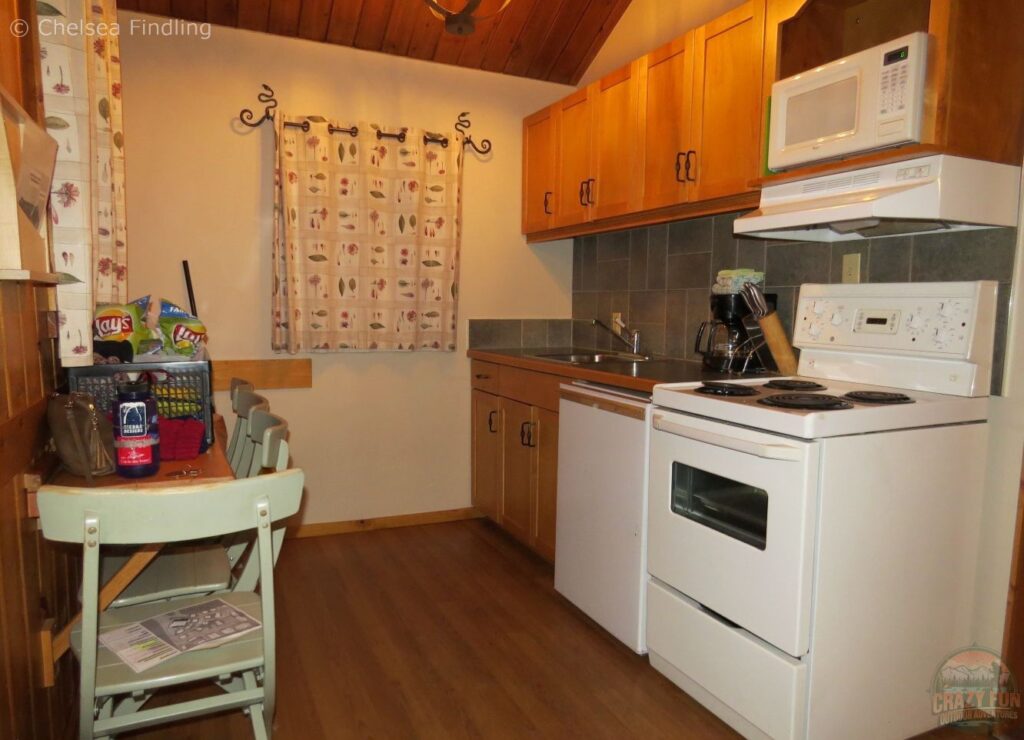 Inside a full kitchen at Bear Hill Lodge in the Canadian Rockies showing kitchen appliances, countertops, cabinets, and dining space.