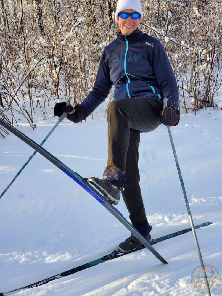 Woman holding up a ski Fjelltech M44 Skin Skis in a snowy mountain setting.