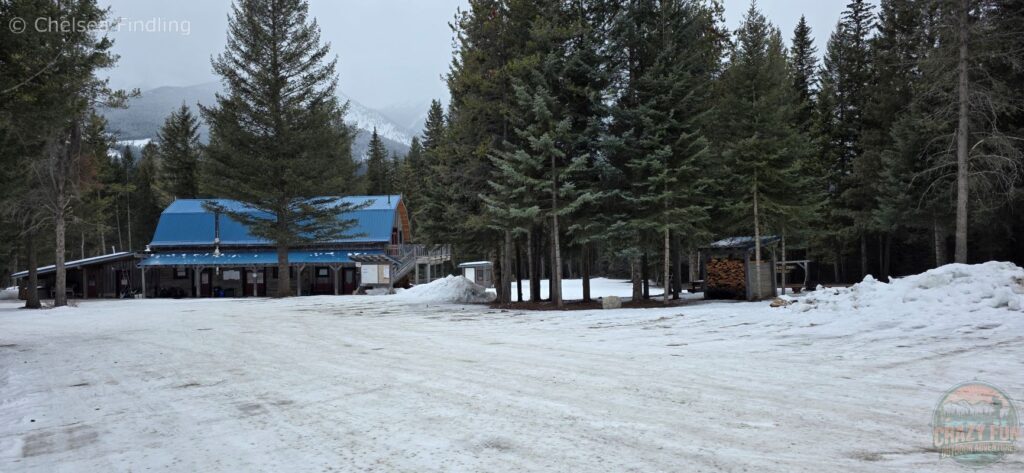 Parking lot in front of a rustic mountain lodge with forested peaks in the background at Nipika Mountain Resort.