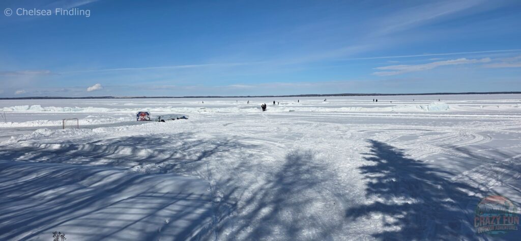 View from a snowy walking path overlooking the frozen ice at Pigeon Lake, with a wide winter landscape stretching across the lake.