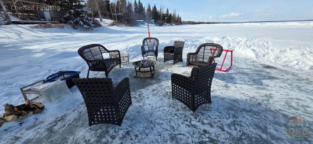 Chairs sitting around a fire pit on the ice. 