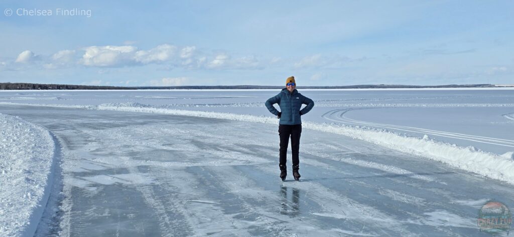 A woman ice skating on Pigeon Lake skateway, surrounded by a snowy landscape.