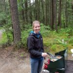 Woman cooking food on a portable camping stove outdoors using her camping gear.