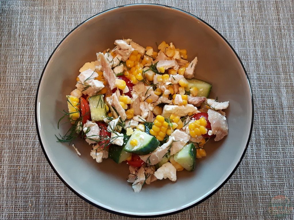Fresh summer salad with colorful mixed greens, tomatoes, cucumber, and other seasonal vegetables served in a bowl.