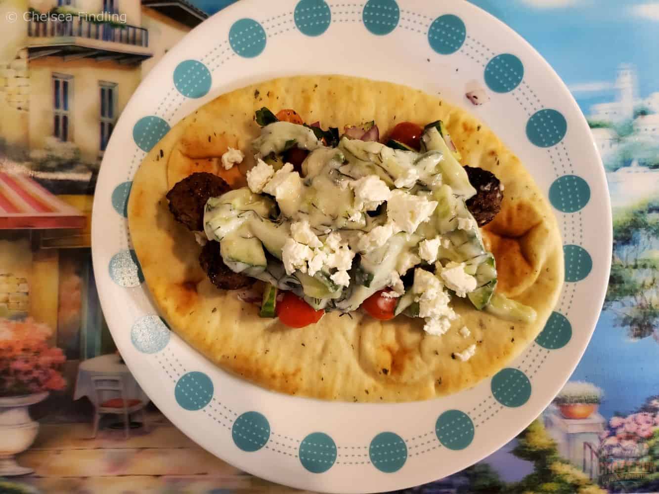 Chicken gyro served on a plate with warm pita, seasoned chicken, fresh vegetables, and a creamy sauce.