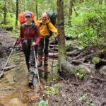 Two backpackers hiking through the forest on the West Coast Trail with backpacks, following a backpacking gear list for a multi-day adventure.