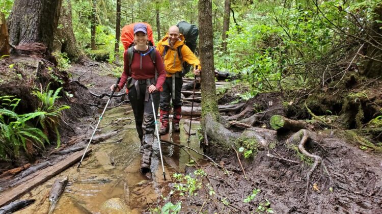 Two backpackers hiking through the forest on the West Coast Trail with backpacks, following a backpacking gear list for a multi-day adventure.