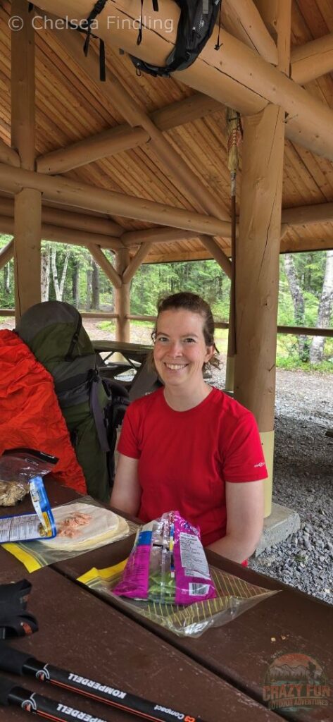 A woman eating a fresh lunch of peas, a wrap, and tuna before the steep climb to Emperor Falls.